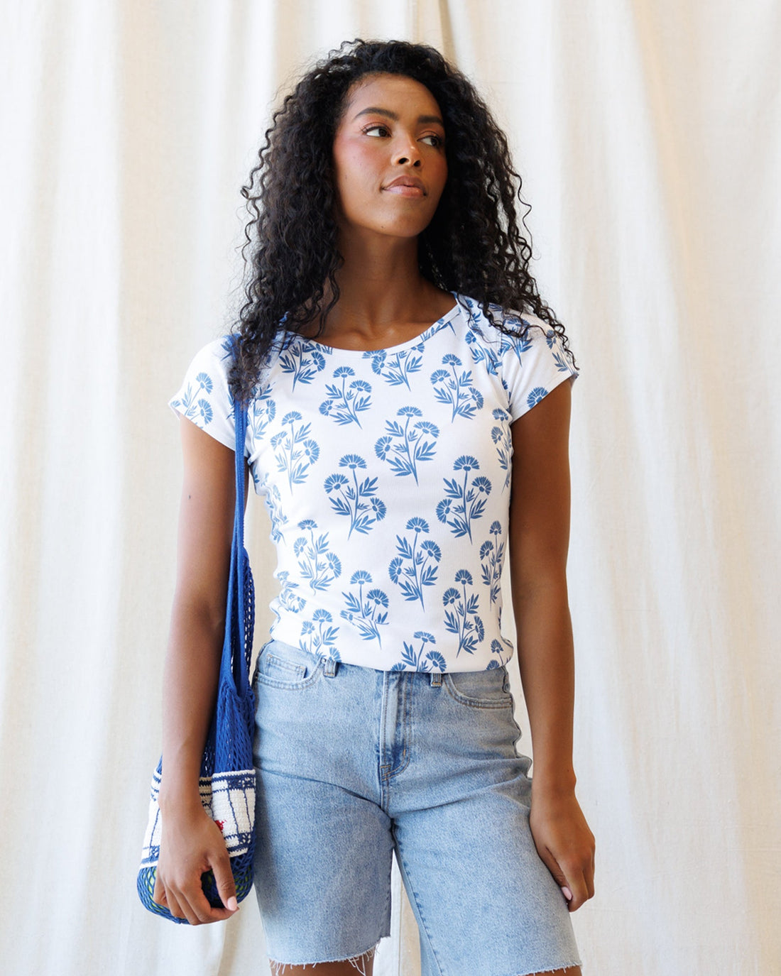 Model wearing an Artistic Tee graphic t-shirt with floral design, paired with stylish denim shorts.