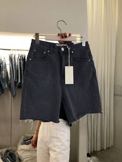 Black denim skirt on a hanger with a tag in a clothing store.