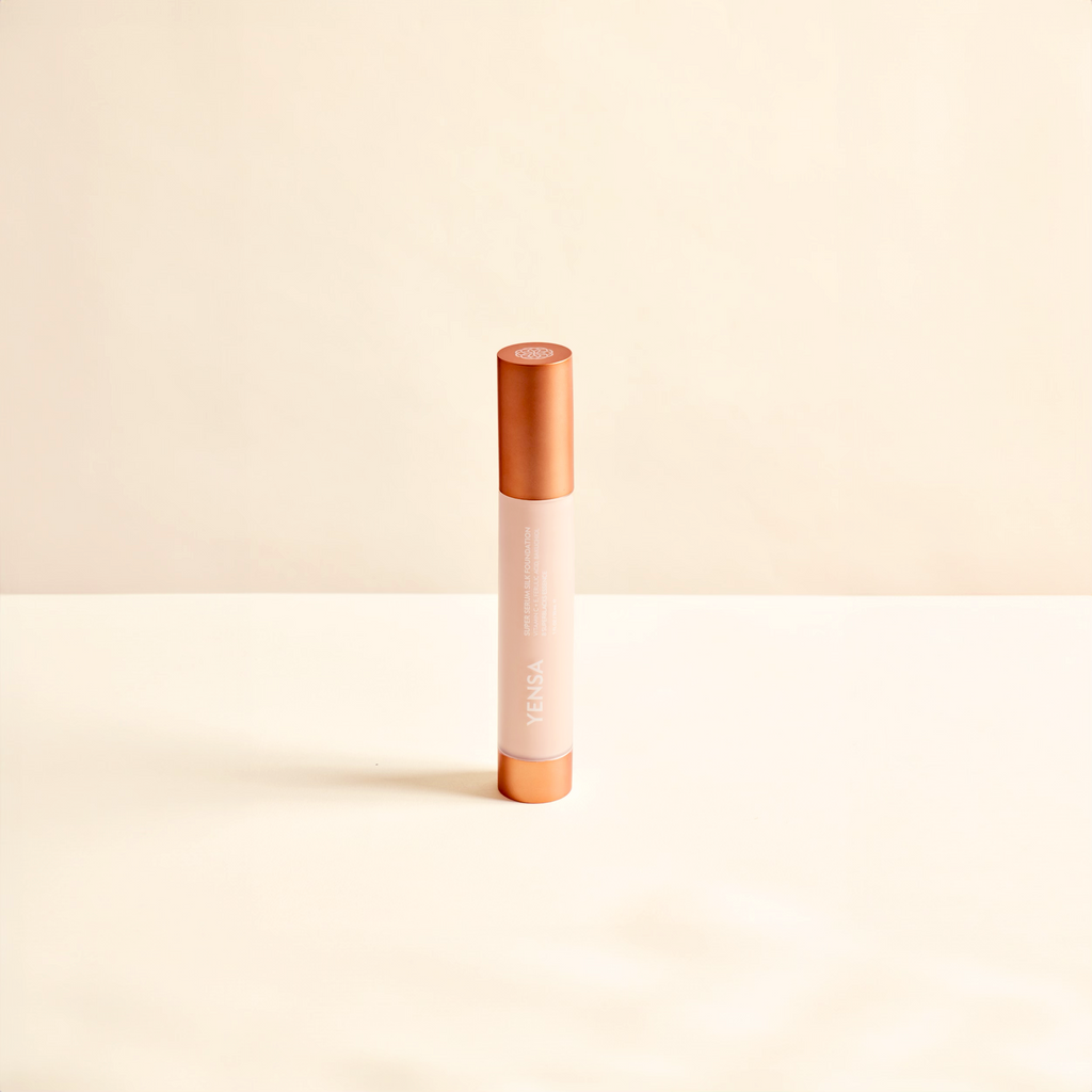 Cosmetic concealer stick with rose gold cap and body on a beige background