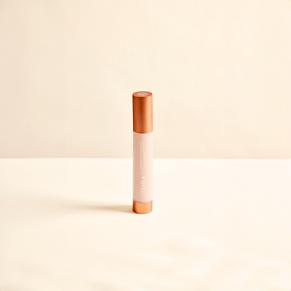 Cosmetic concealer stick with rose gold cap and body on a beige background