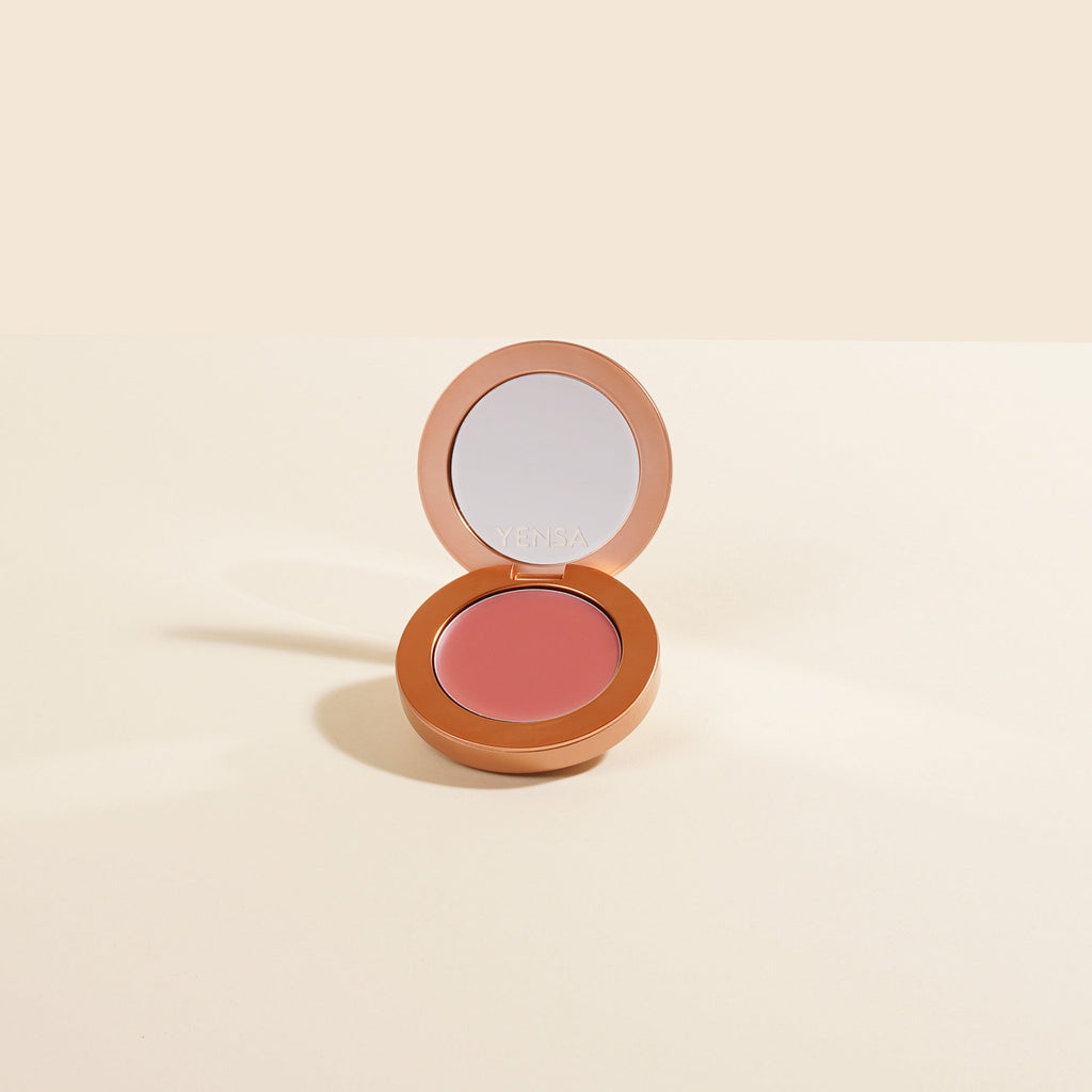 Compact blush in a round, open case on a beige background