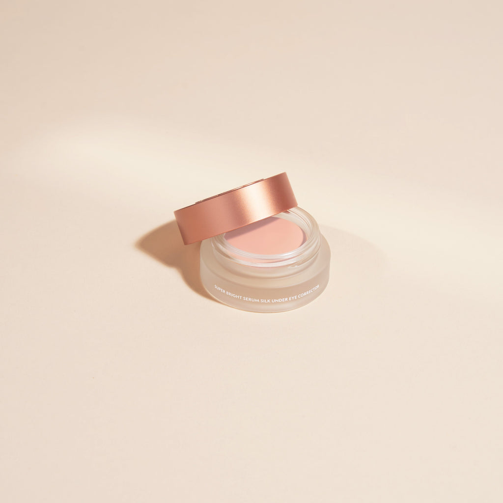Cosmetic jar with rose gold lid on a beige background